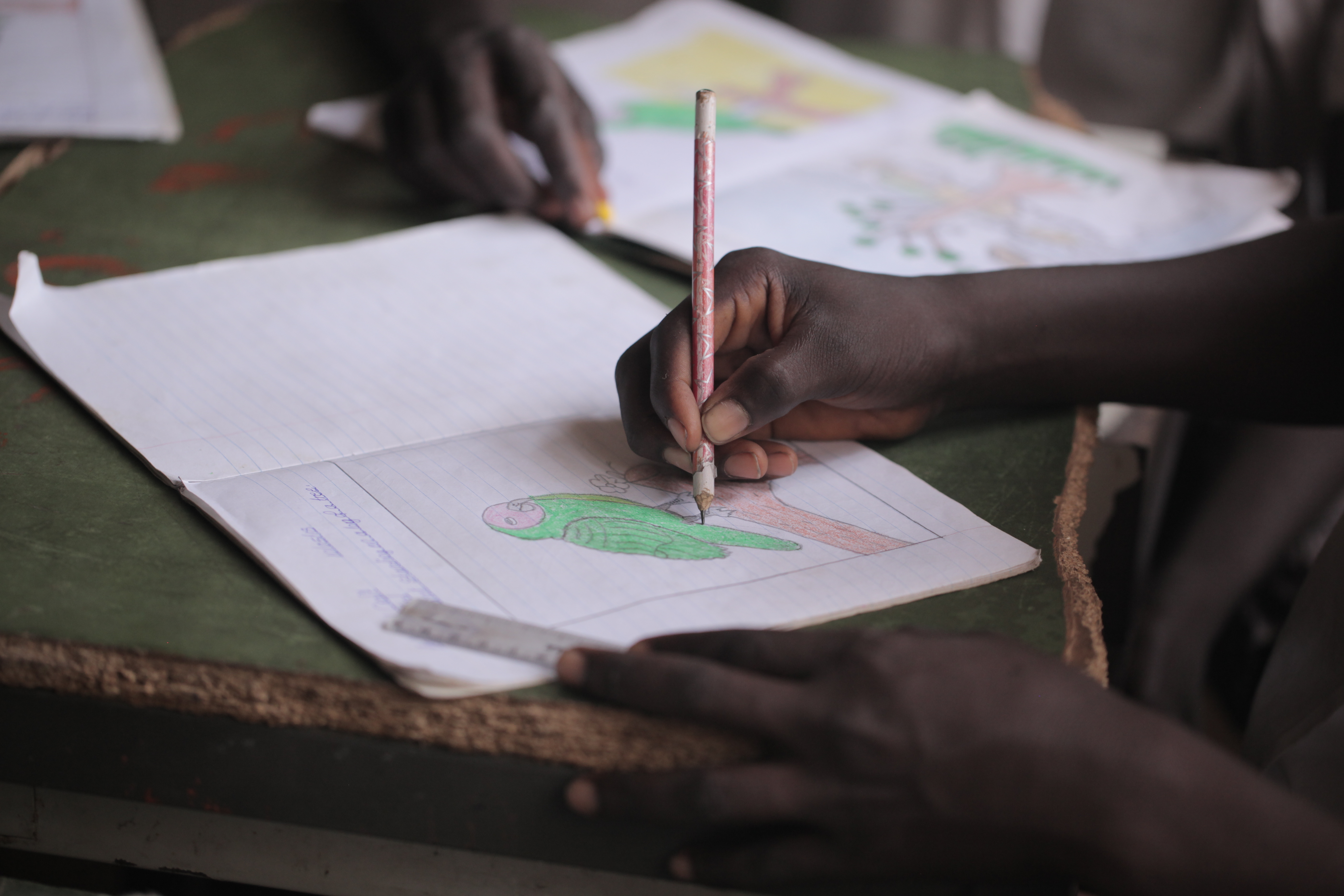 african education close up - macro photography of a black african school kid hand holding a pencil, inside a classroom in the Gambia, Africa