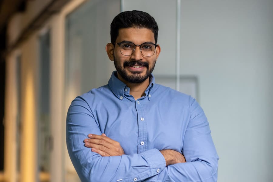 Un enseignant-chercheur portant des lunettes et un chemise. Il a les bras croisés et semble souriant.
